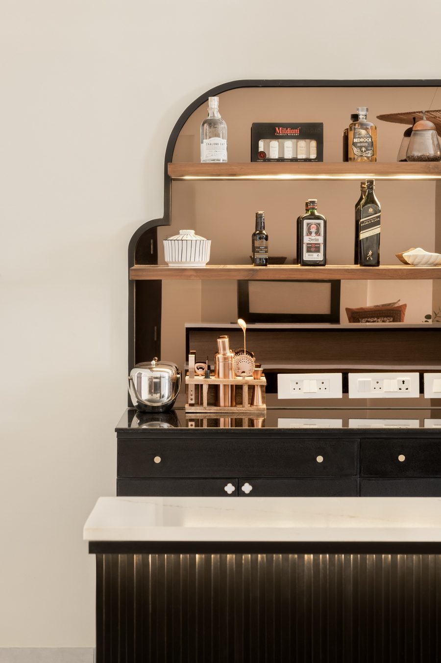 Arched bar niche in dark wood with warm-lit shelving