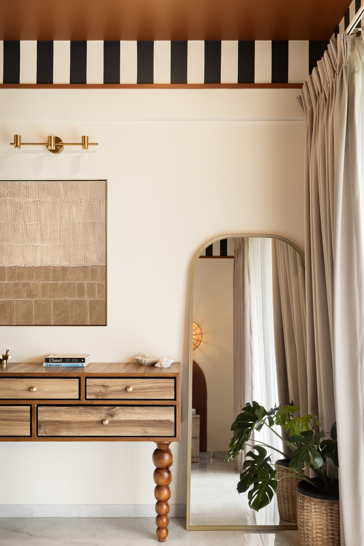 Bobbin-legged console and arched mirror beside the curtain in the striped-band bedroom