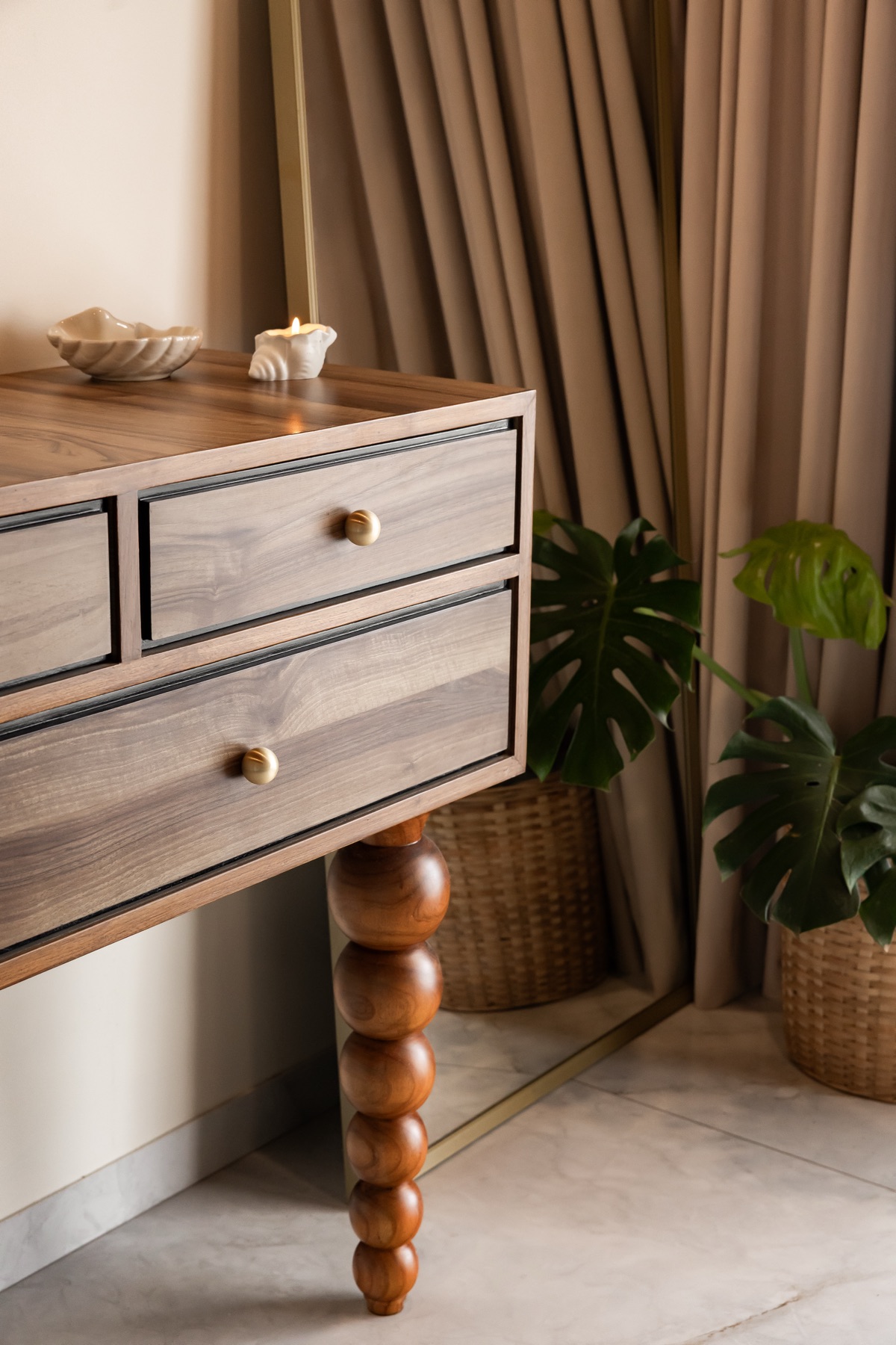 Bobbin-legged console in pale timber with brass pulls, backed by a full-length mirror