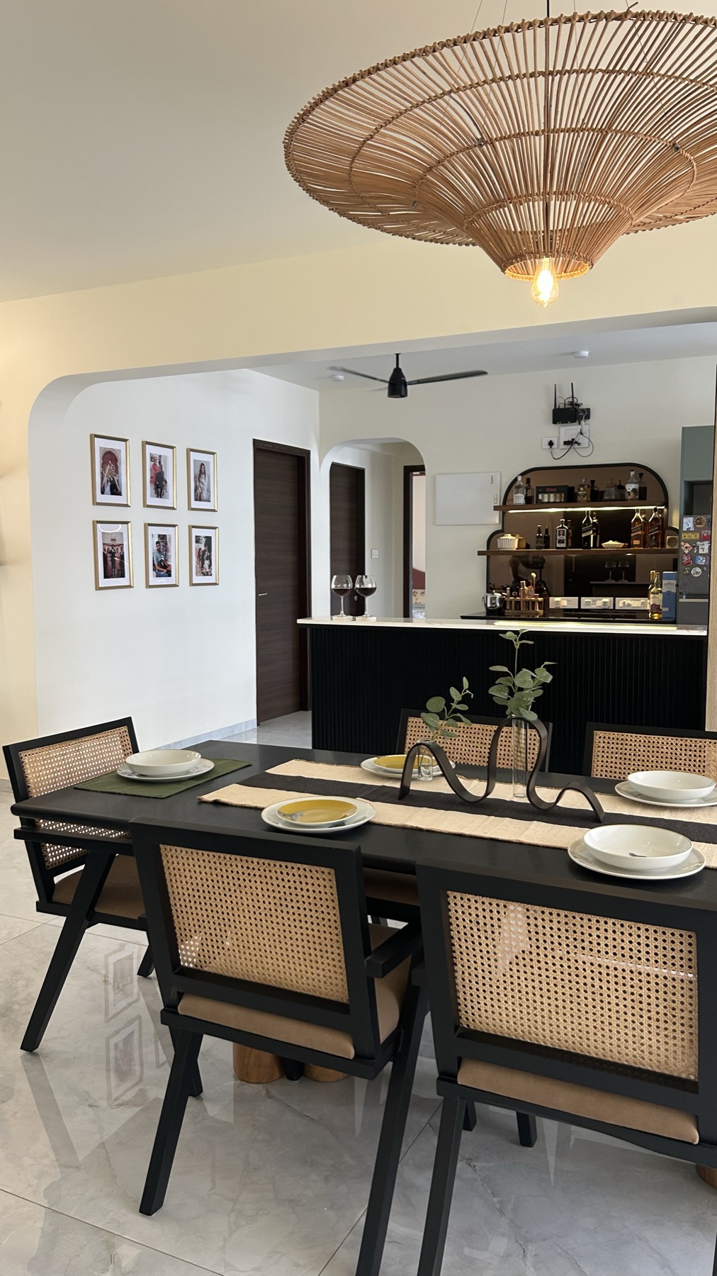 Dining area looking through to the kitchen counter under a wide rattan pendant