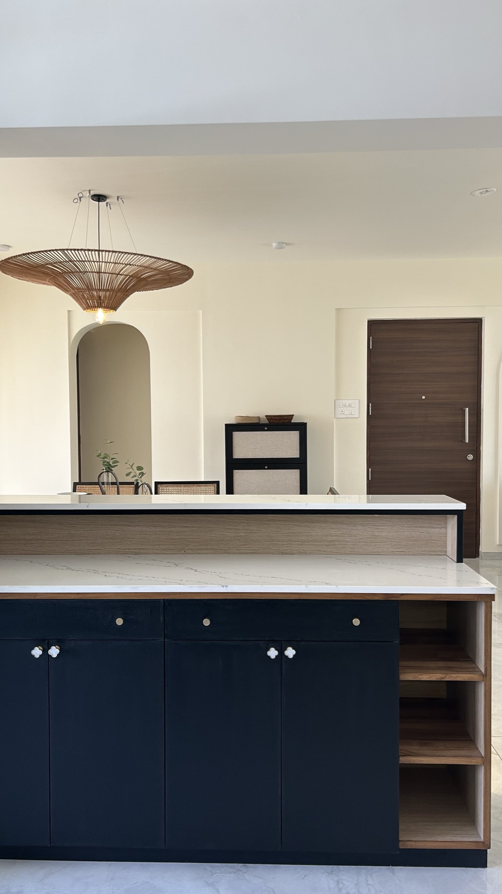 Kitchen island in deep navy with a white stone counter and open timber shelving