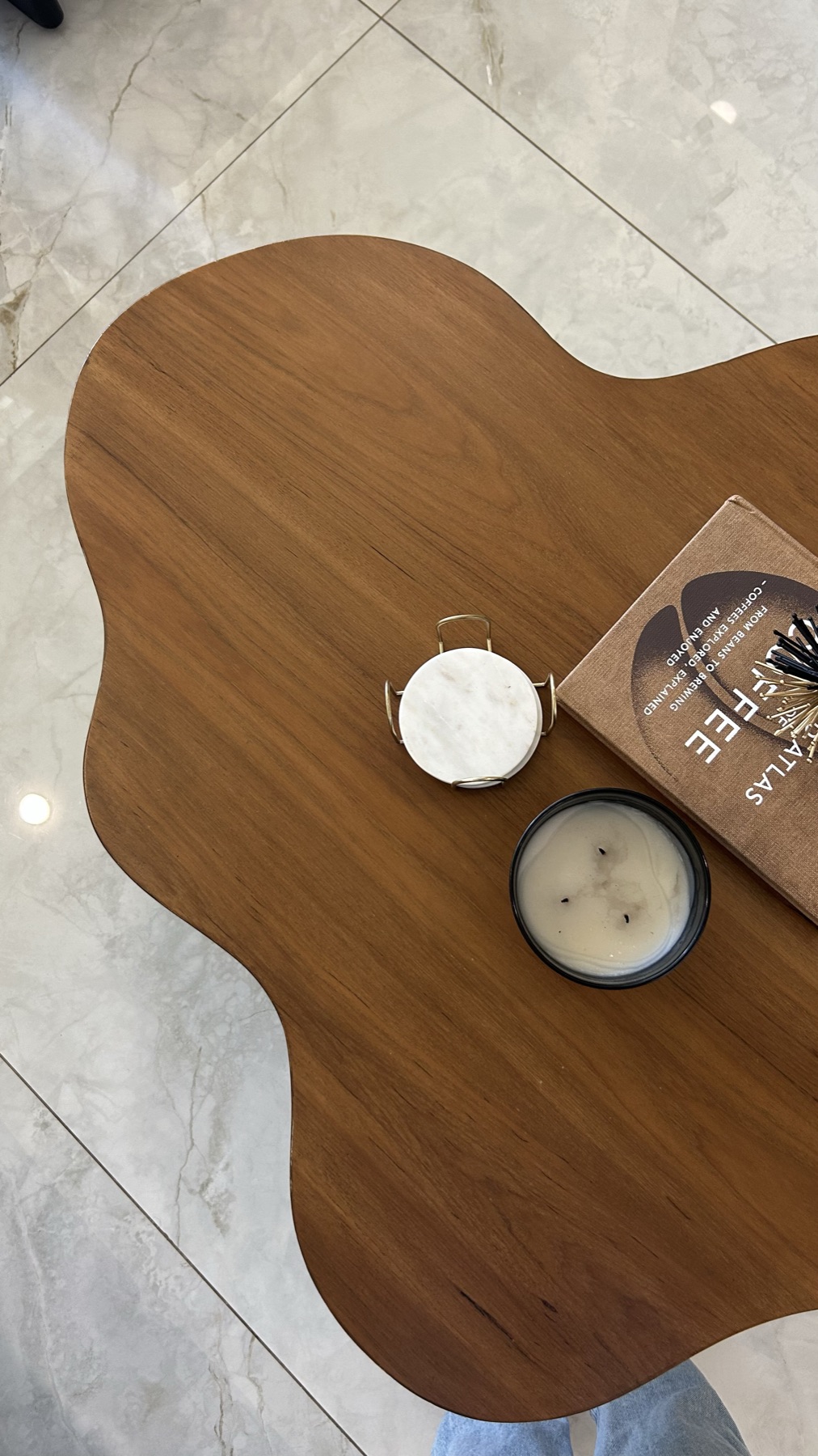 Curved coffee table from above with a candle, coaster and book