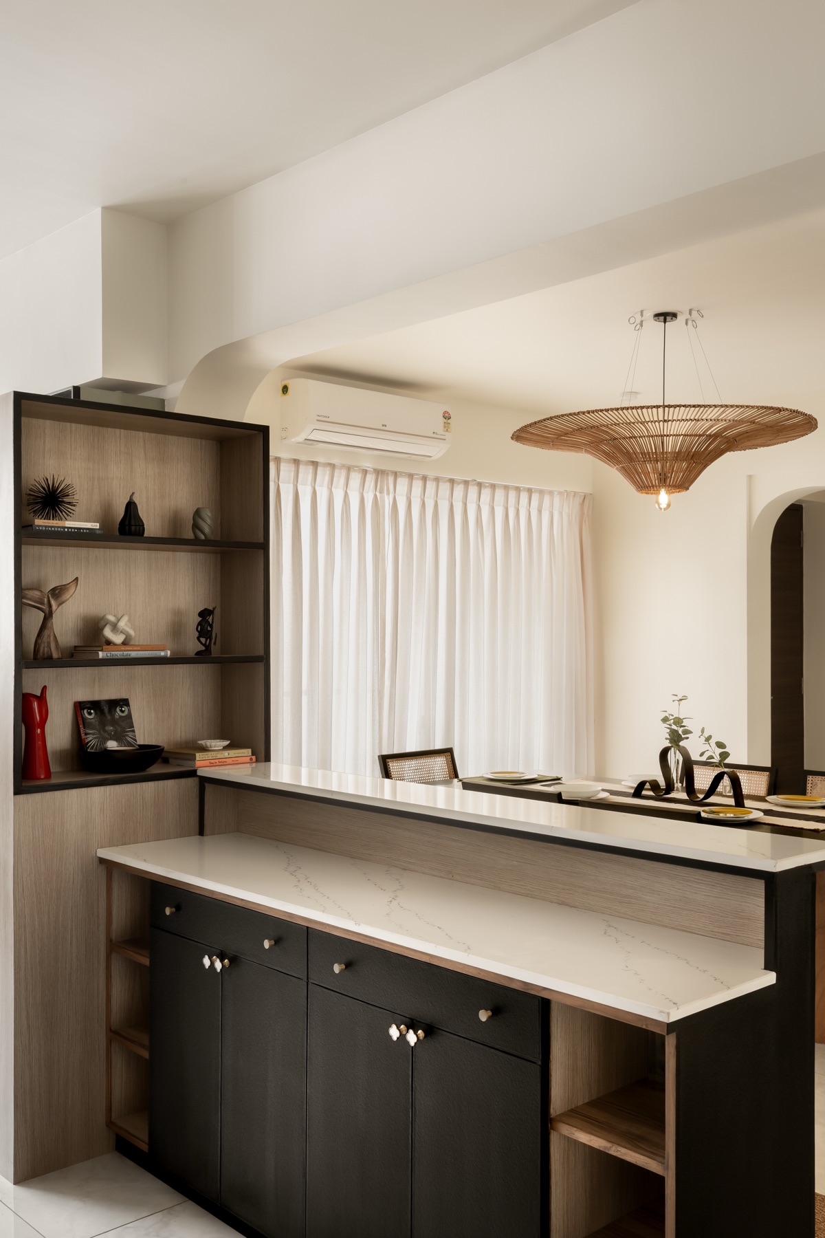 Crockery unit in dark timber with a stone counter beside the rattan-lit passage