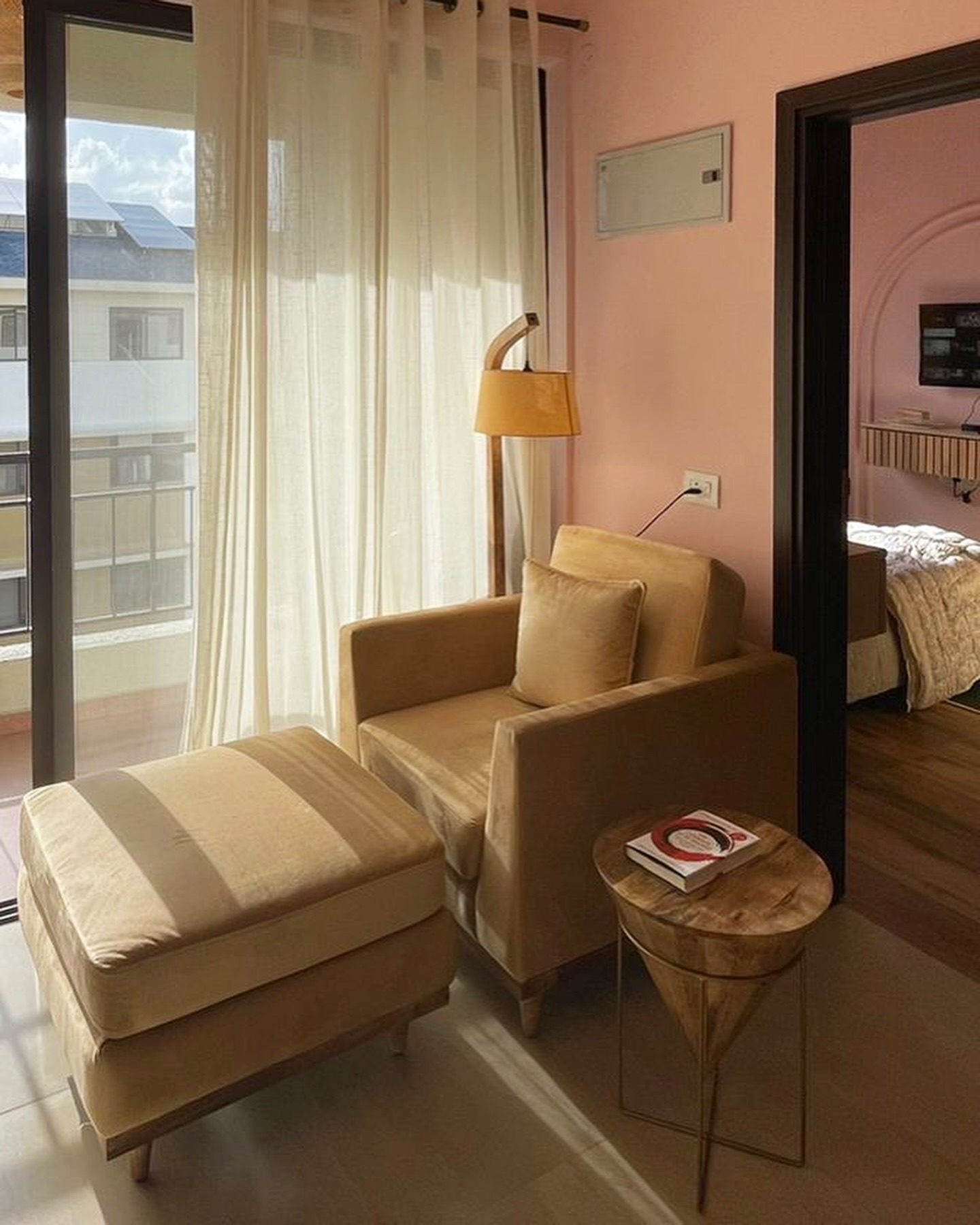 Tan armchair and ottoman by the balcony doors in the pink living room
