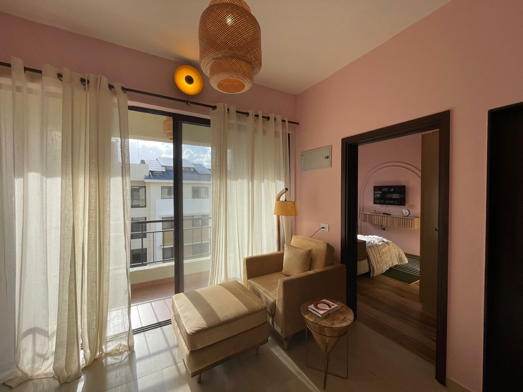 Bedroom opening to the balcony, with a woven pendant and full-length mirror