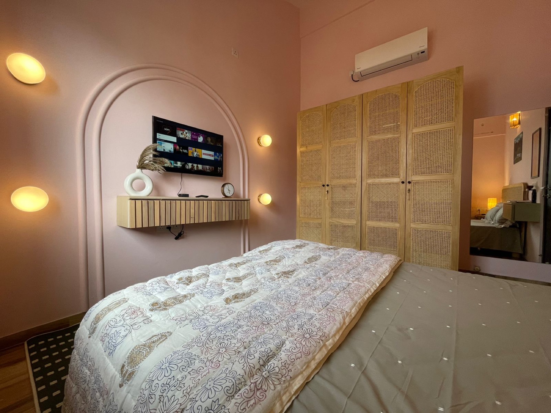 Arched alcove holding the television above a slim ledge in the pink bedroom