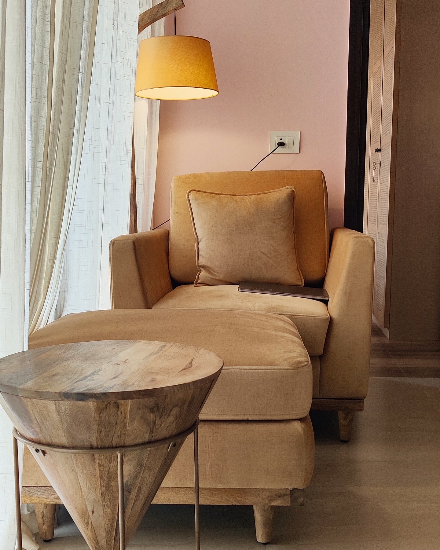 Tan chaise and turned wooden side table under a mustard shade
