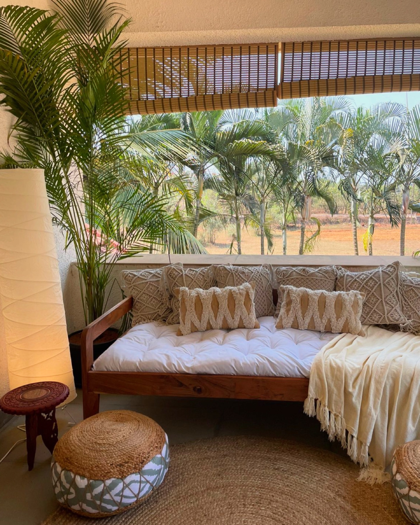 Cane daybed under a bamboo blind, looking out to coconut palms