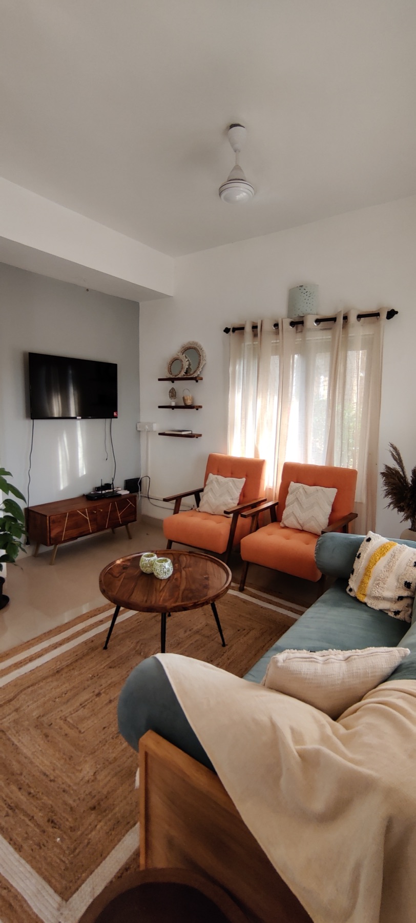 Living room towards the television wall, with orange armchairs and the teak-framed sofa