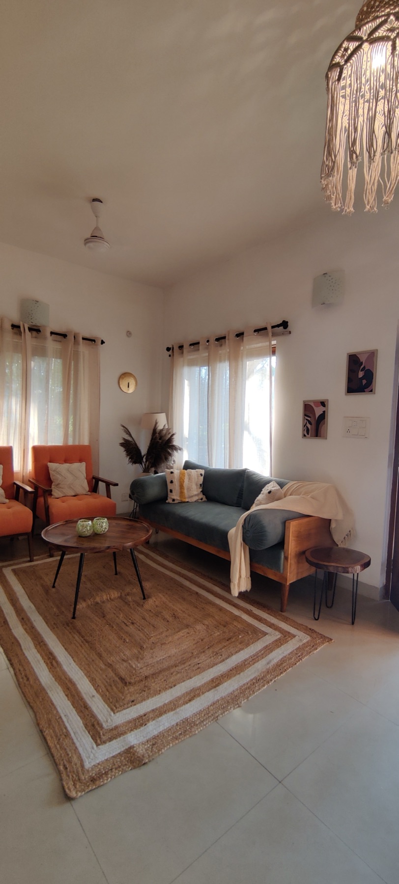 Living room seen from the entry, a macrame pendant overhead and the bordered jute rug running the length of the floor