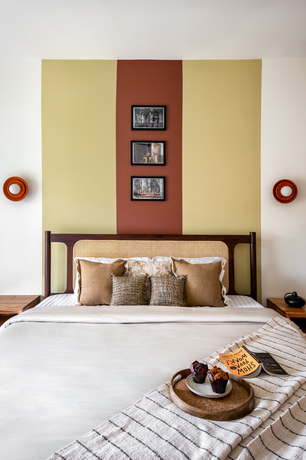 Bedroom headboard wall painted in olive and terracotta bands with a trio of framed prints