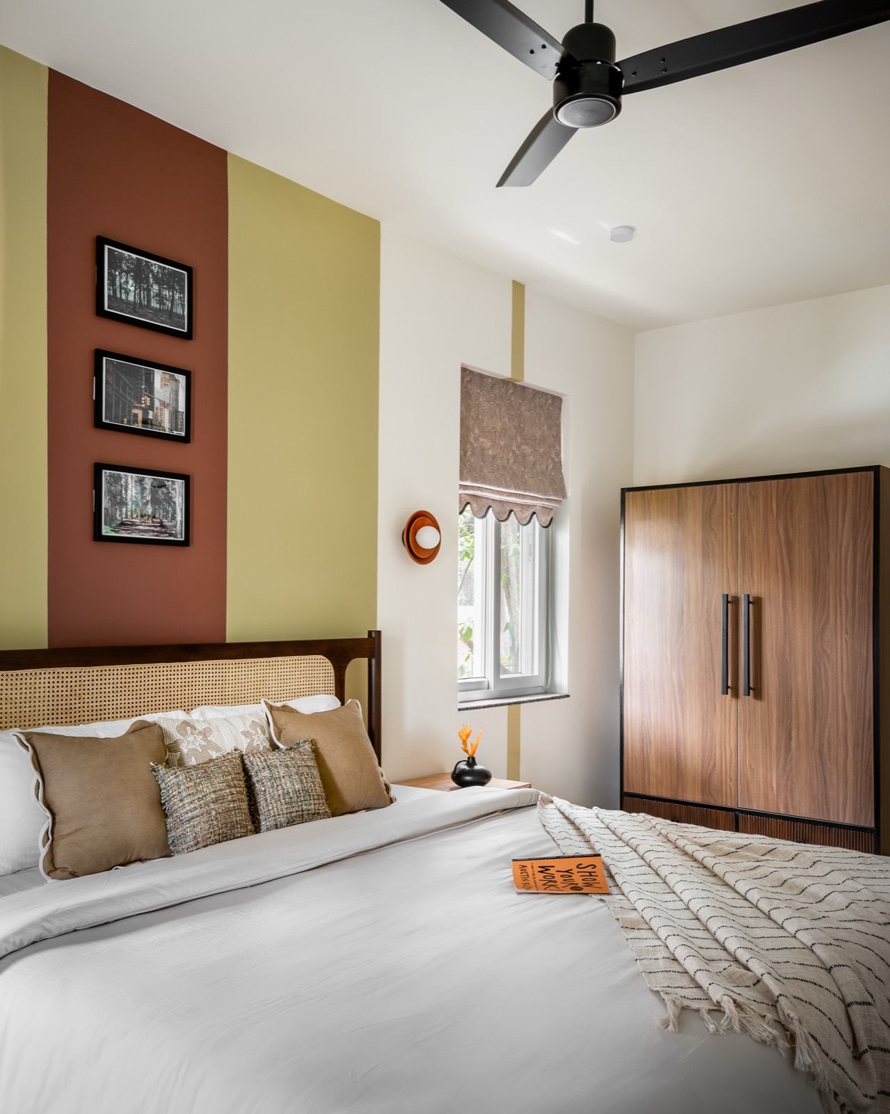 Olive and terracotta bedroom seen towards the wardrobe and window with a scalloped blind