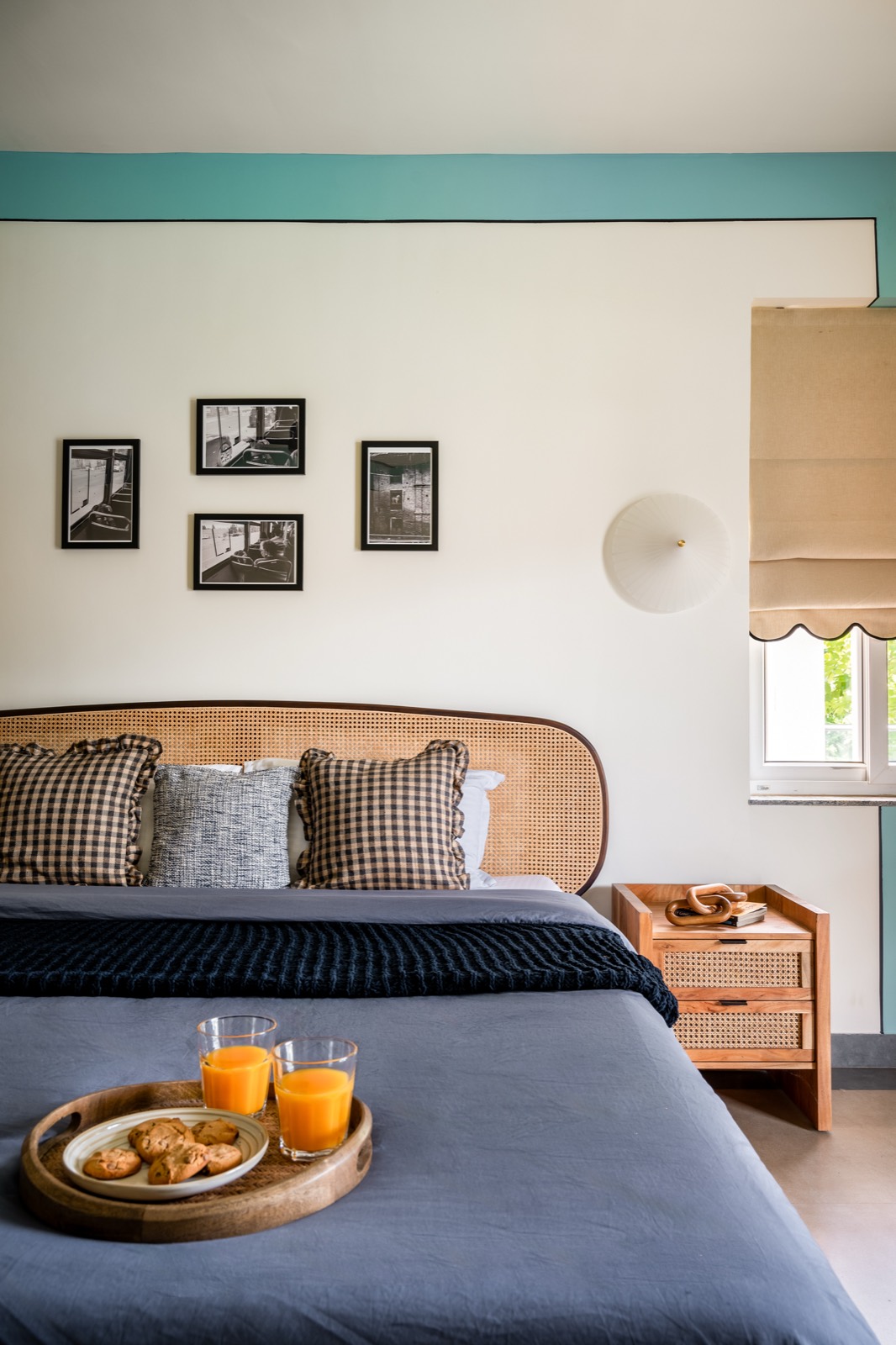Bedroom with a fine sea-green band at ceiling height, curved cane headboard and gingham cushions