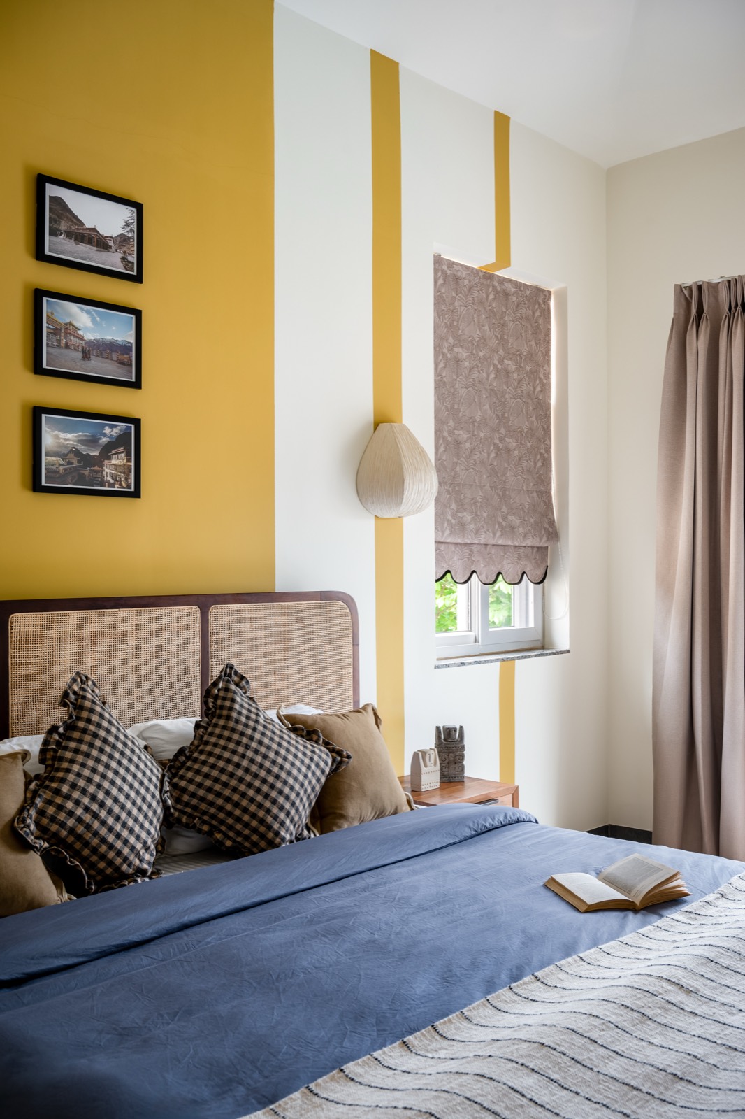 Framed landscape prints on the mustard band beside a scalloped jute blind