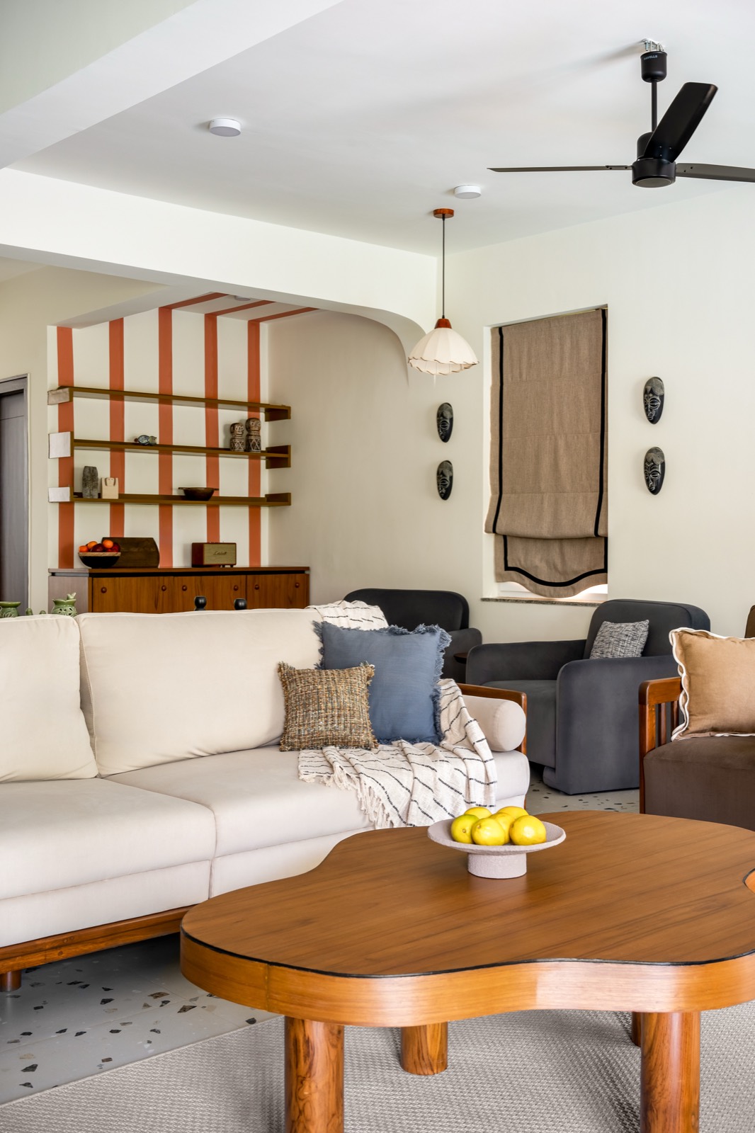 Living room seating with ivory sofa, denim cushions and a view through the arch to the terracotta-striped shelving