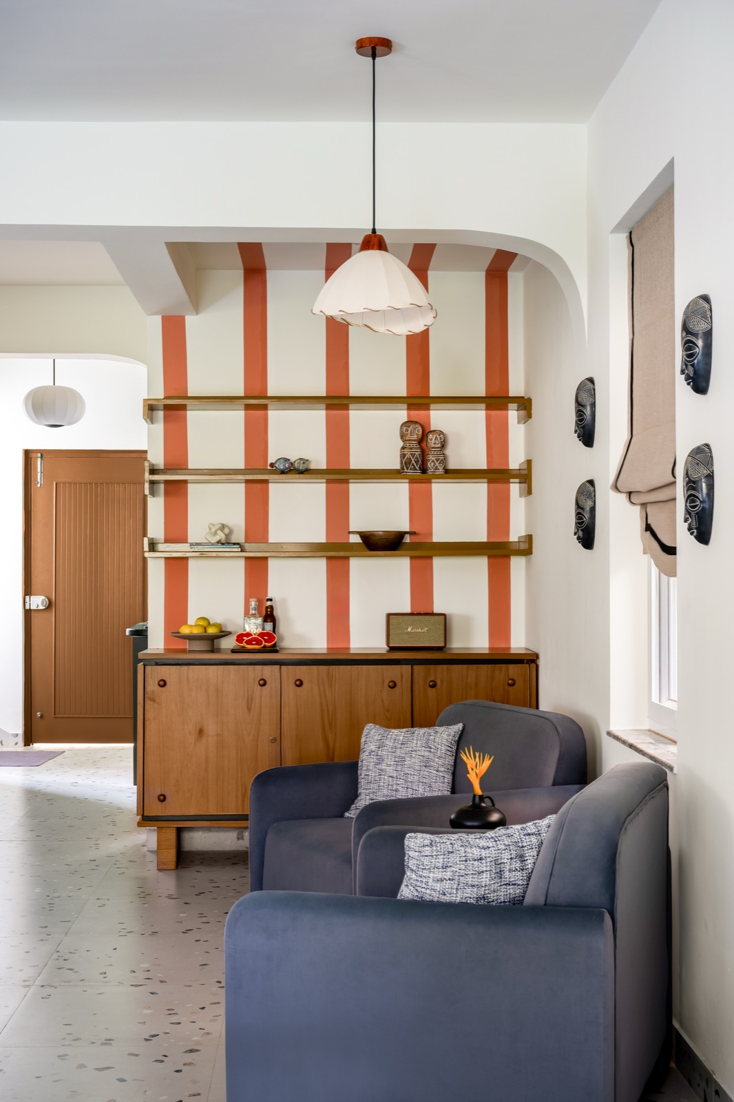 Brass-railed shelving set against terracotta stripes above a teak sideboard