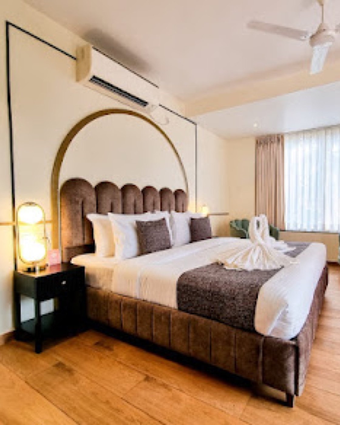 Mademoiselle guest room with an arched gilt headboard niche and brass lamp