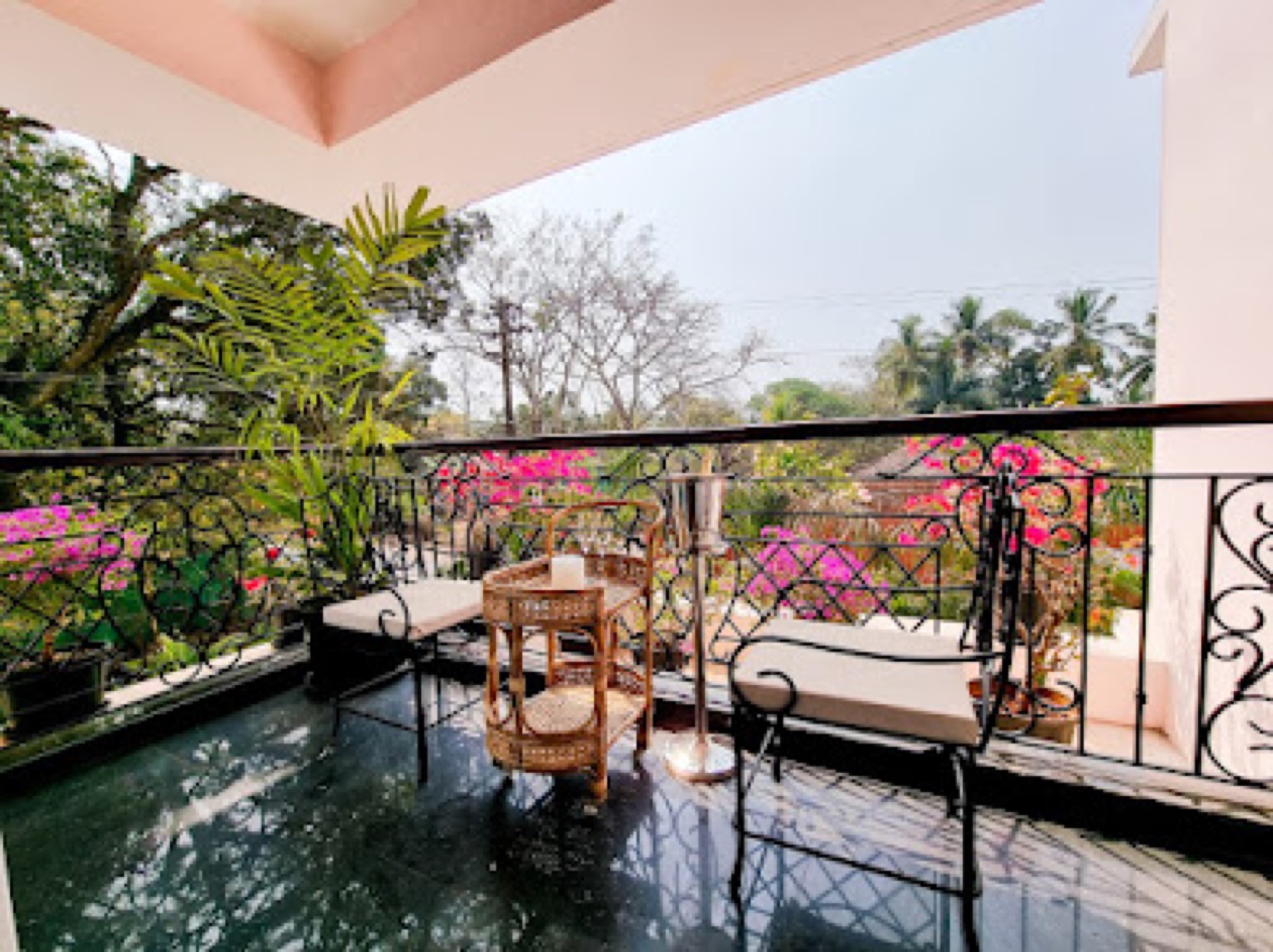 Balcony seating above the water, framed by bougainvillea and palms