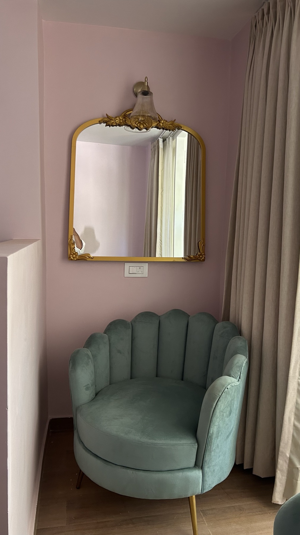 Mint scalloped armchair on brass legs beneath a gilt mirror