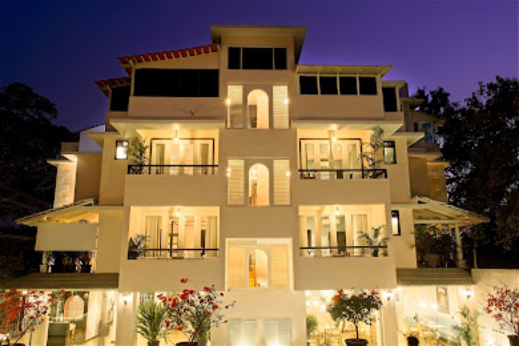 The hotel lit at dusk, its tiers of arched balconies stacked above the garden