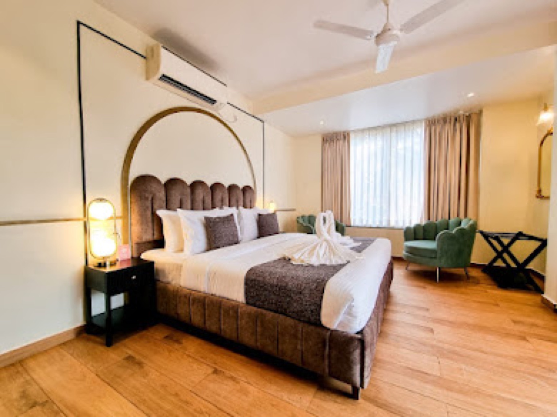 Guest room with an arched mirrored headboard, brass lamps and a green velvet chair