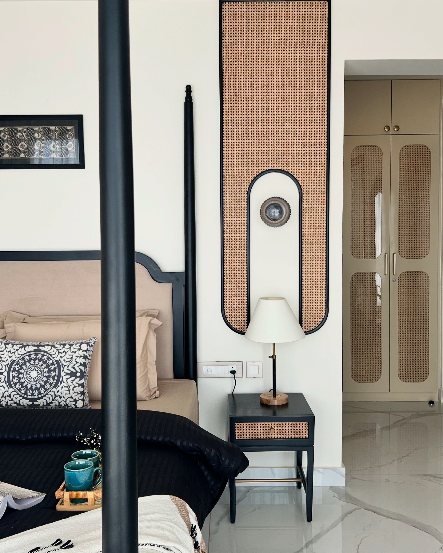 Black four-poster bed beside a cane wall panel and cane-fronted wardrobes