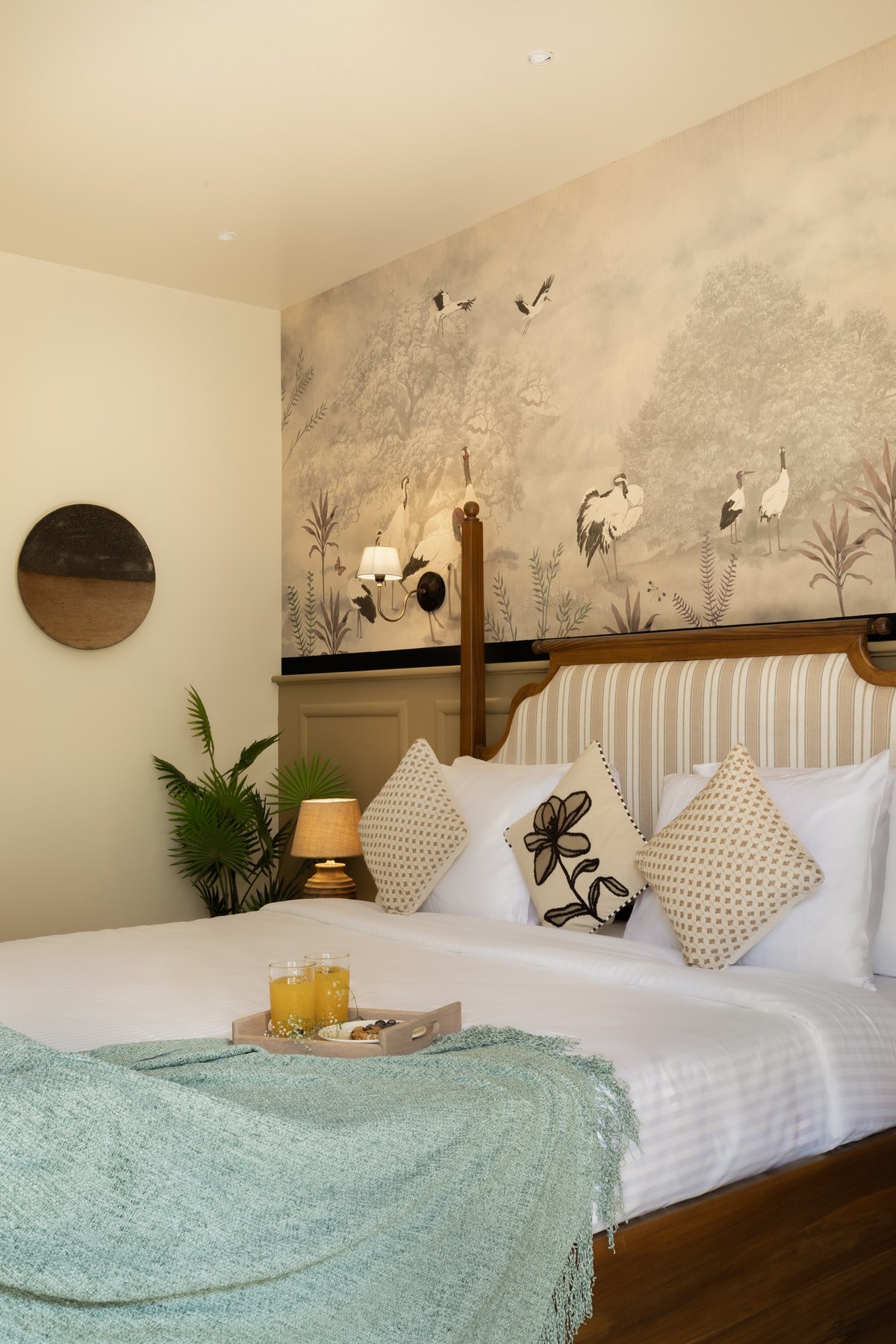 Bed dressed in mint and white below the crane mural