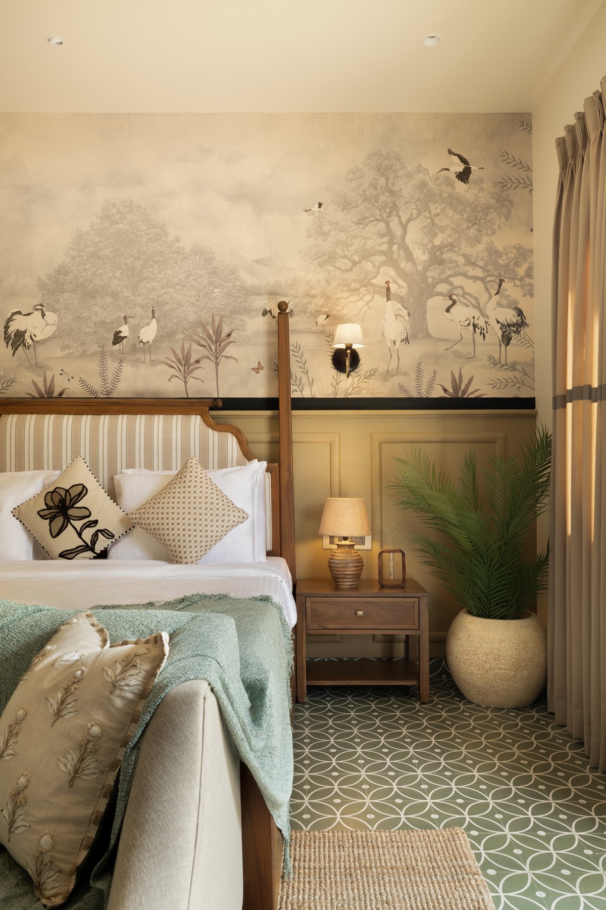 Crane mural above the bed, with a potted palm in the corner
