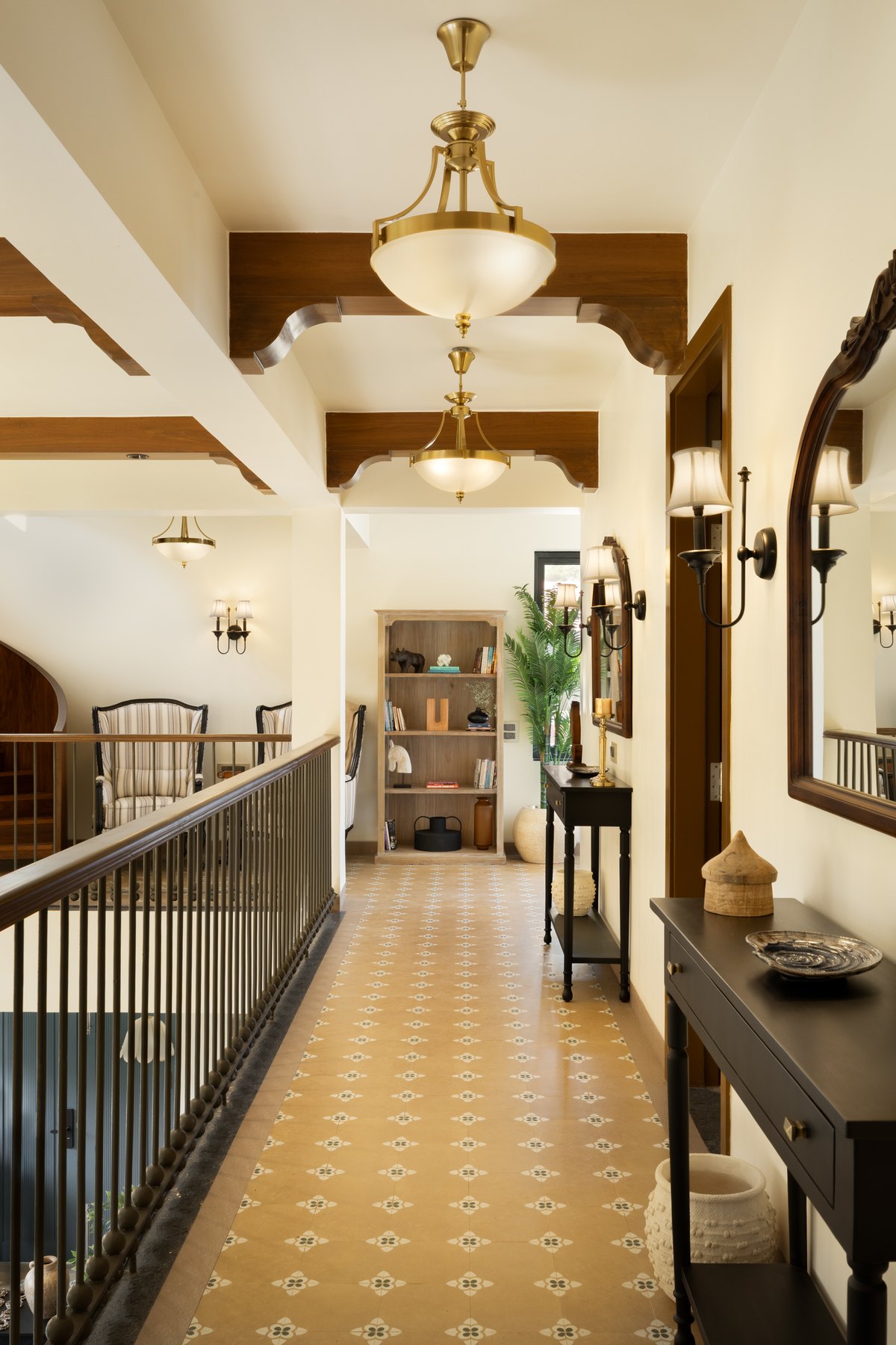 Upstairs corridor with brass pendants, an arched doorway and a console against the railing