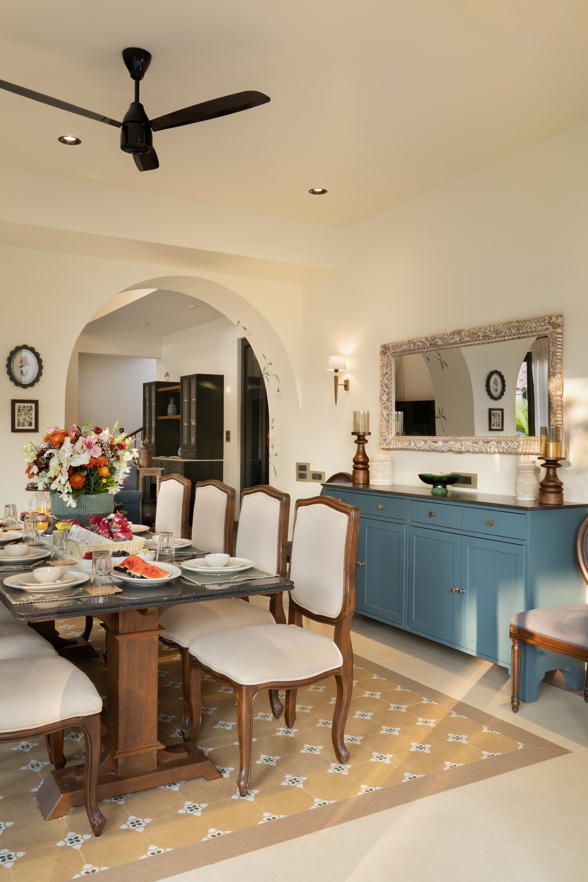 Dining table laid beneath a carved mirror, with a pale blue sideboard alongside