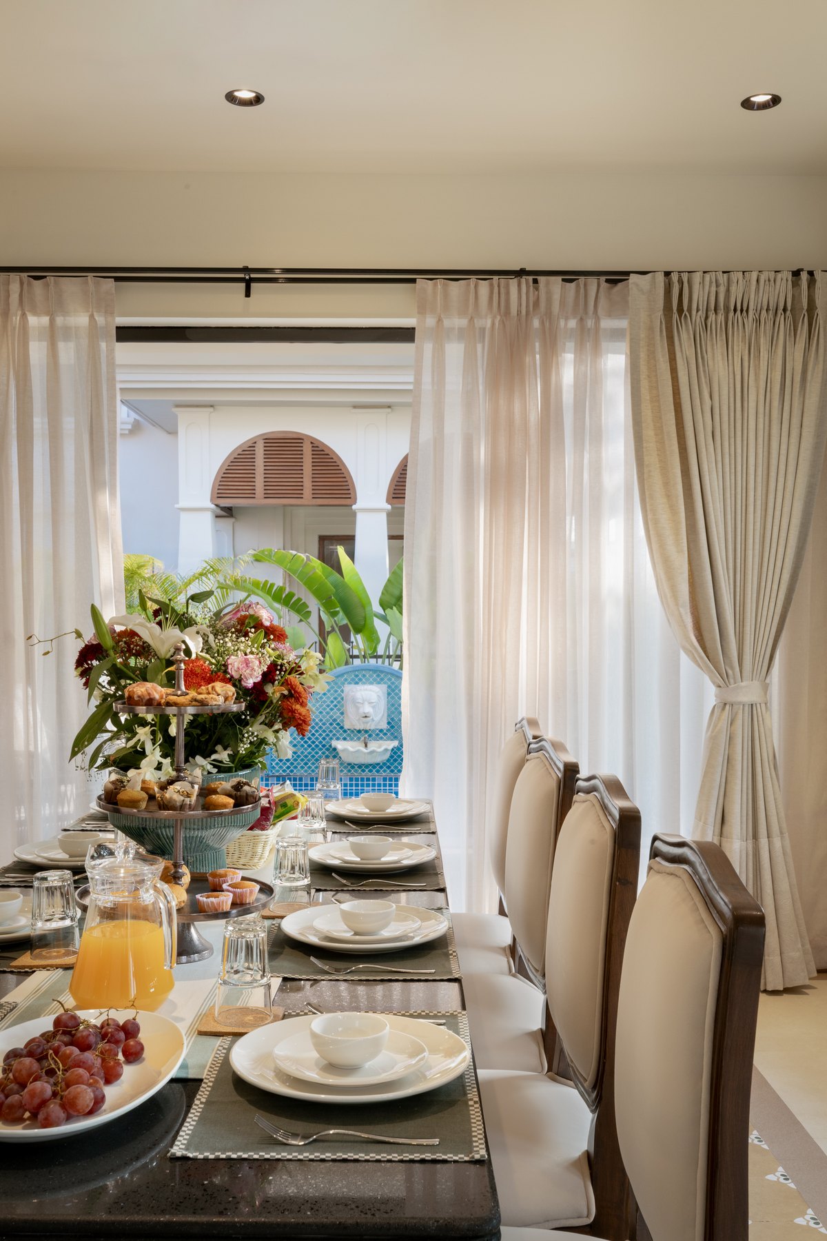 Breakfast laid along the dining table, curtains drawn back to the courtyard