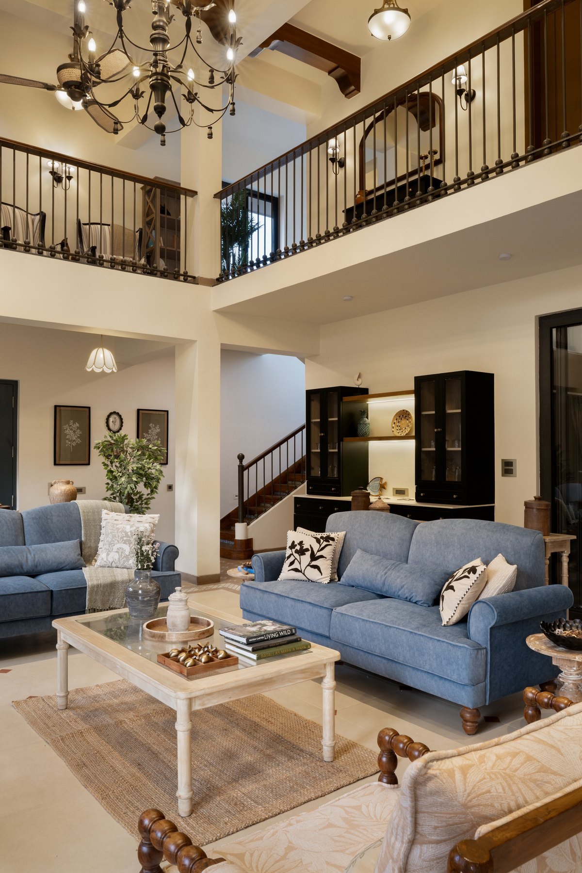 Blue sofas and a painted coffee table below the staircase and mezzanine railing
