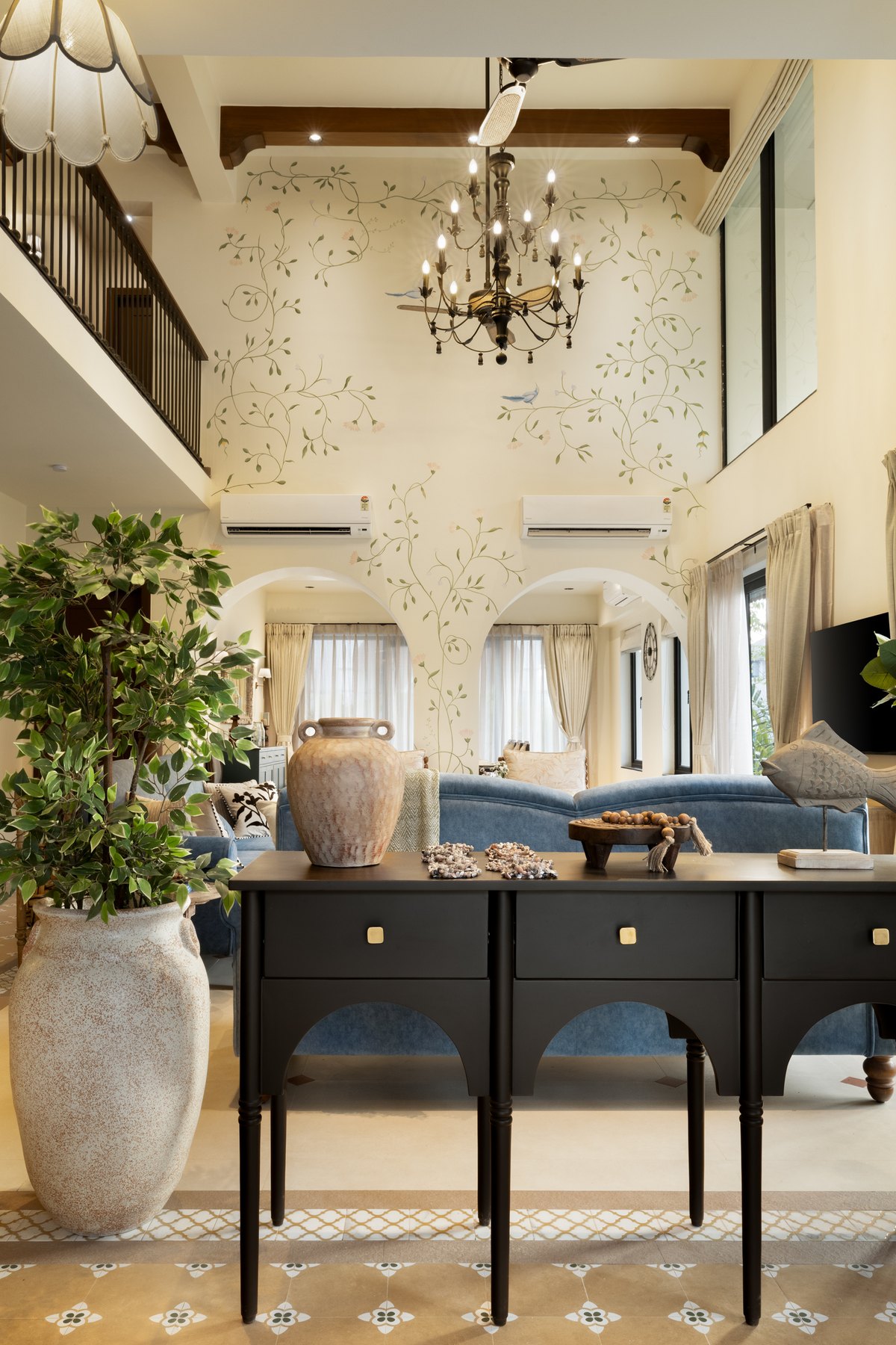 Hand-painted vines climbing the double-height wall above a black console and stone urn