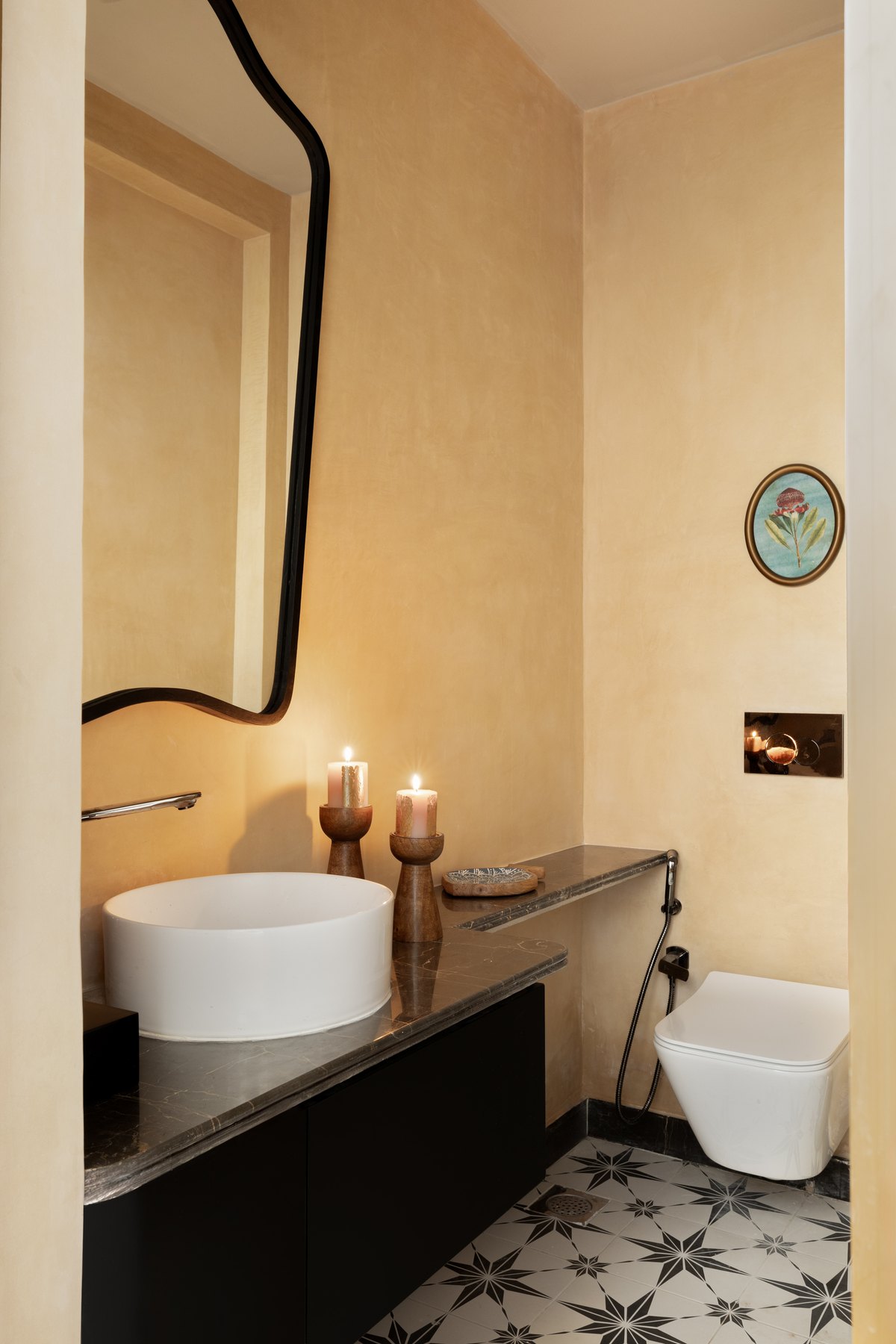 Powder room with a black-framed mirror, stone basin and star-tiled floor