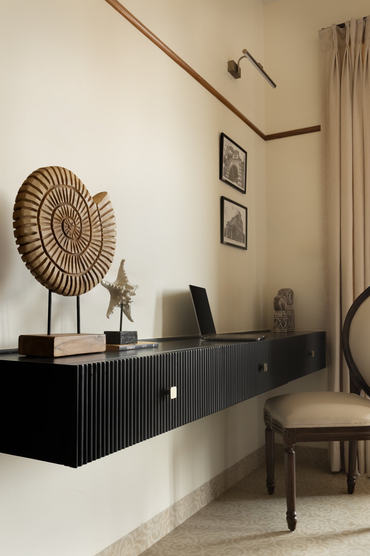 Black fluted desk floating below framed prints and a woven disc