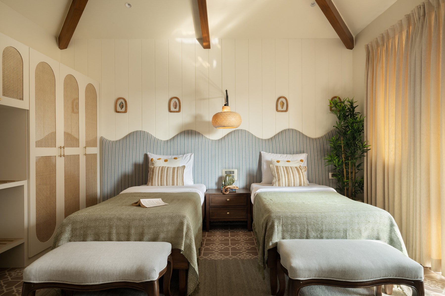 Twin beds under a sloped beamed ceiling, scalloped blue panelling behind
