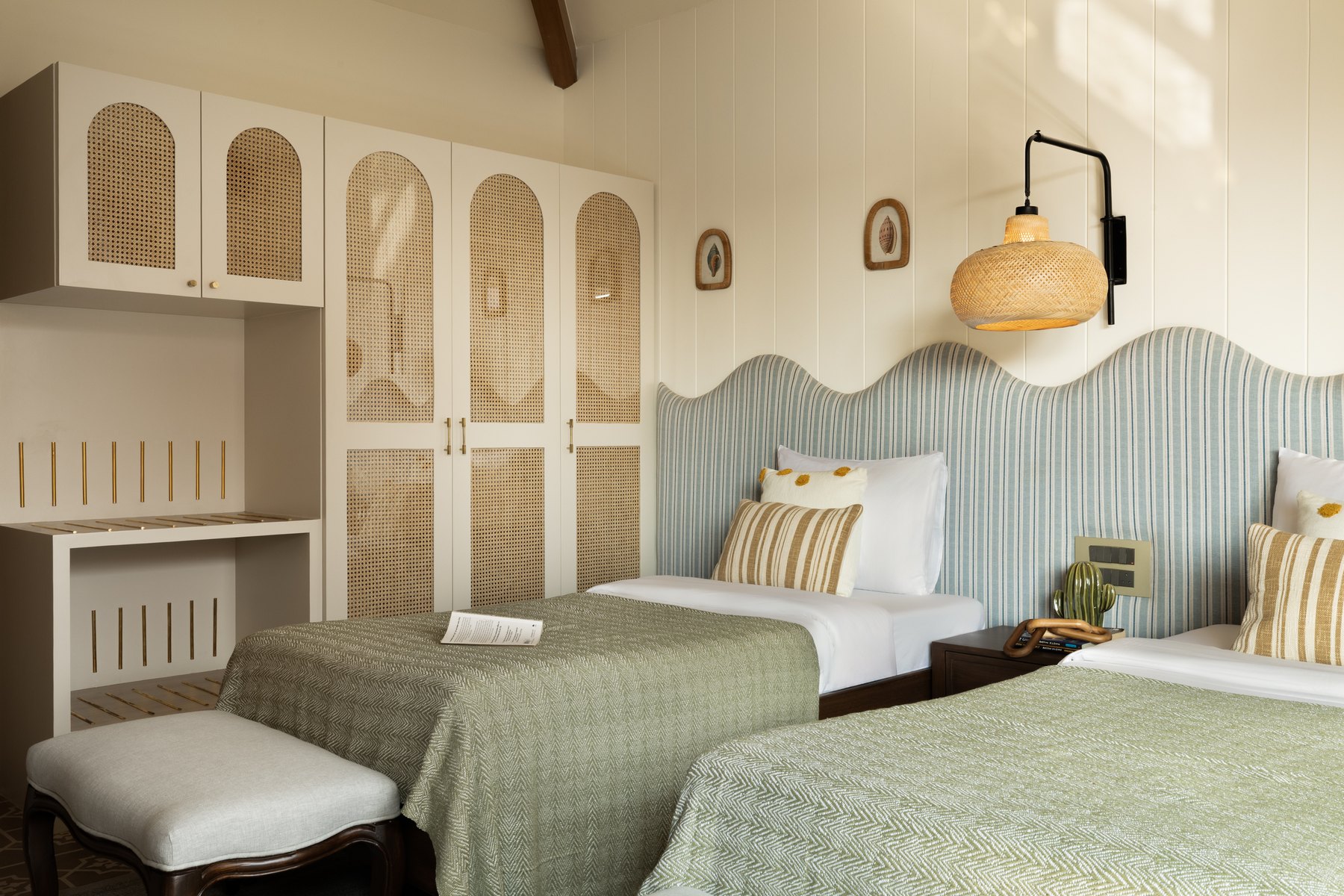 Cane-fronted wardrobes beside the twin beds dressed in green